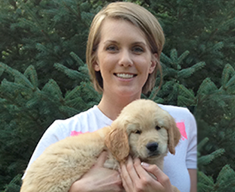 outdoor photo of woman holding a golden retriever puppy