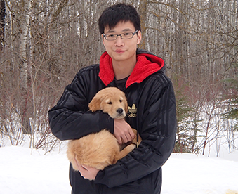 outdoor photo of man holding a golden retriever puppy