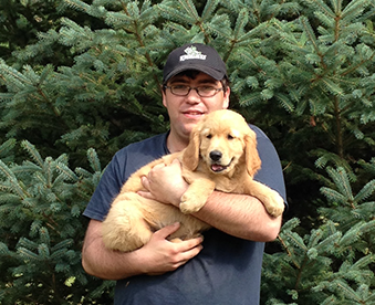 outdoor photo of man holding a golden retriever puppy