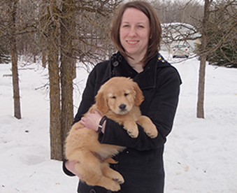 outdoor photo of woman holding a golden retriever puppy