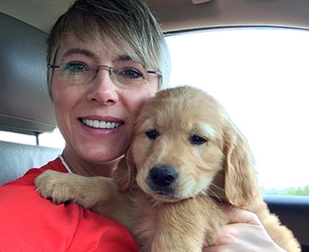 close up of woman in car holding a golden retriever puppy