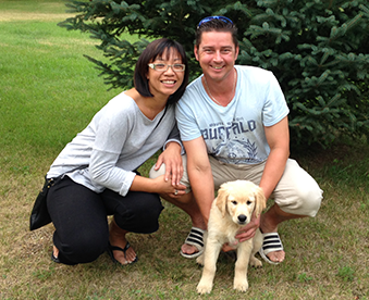 outdoor photo of a couple with their newly adopted golden retriever puppy