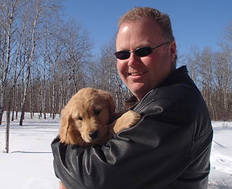 outdoor photo of man holding a golden retriever puppy