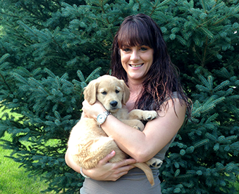 outdoor photo of woman holding a golden retriever puppy