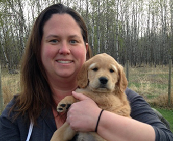 outdoor photo of woman holding a golden retriever puppy