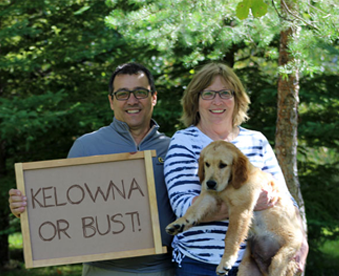 outdoor photo of a couple holding a golden retriever puppy and a Gotcha Day sign