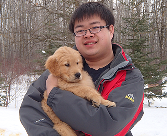 outdoor photo of man holding a golden retriever puppy