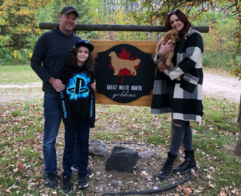 outdoor autumn photo of a family holding a golden retriever puppy and a Gotcha Day sign