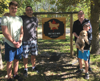 outdoor autumn photo of a family holding a golden retriever puppy and a Gotcha Day sign