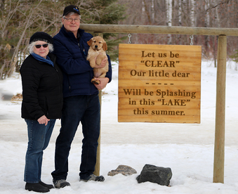 outdoor winter photo of a couple holding a golden retriever puppy and a Gotcha Day sign