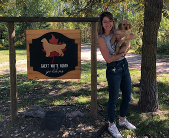 outdoor autumn photo of a woman holding a golden retriever puppy and a Gotcha Day sign